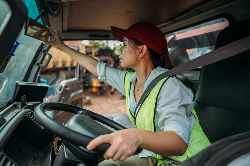A woman confidently driving a truck, focused on the road ahead, displaying determination and independence.